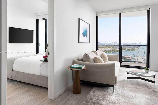 living room with a water view, expansive windows, and light wood-type flooring