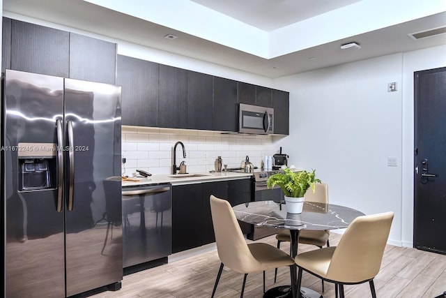 398 NE 5th St Unit 3610, Miami, FL 33132 - kitchen featuring appliances with stainless steel finishes, light wood-type flooring, tasteful backsplash, dark cabinets, and light countertops