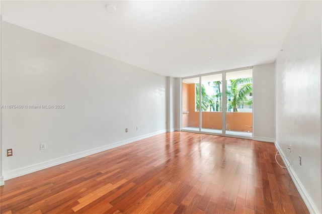 empty room with hardwood / wood-style flooring and expansive windows