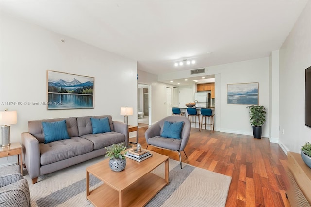 living room with wood finished floors, visible vents, and baseboards