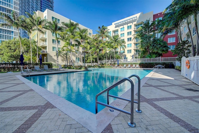 community pool with a patio area and fence