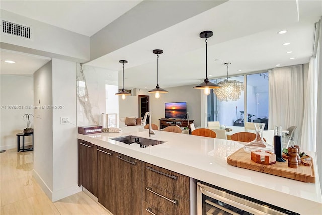 kitchen with dark brown cabinetry, wine cooler, decorative light fixtures, and sink