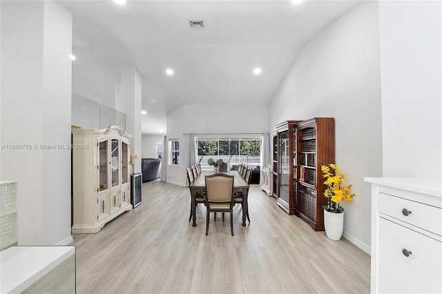 dining room featuring high vaulted ceiling and light wood-type flooring