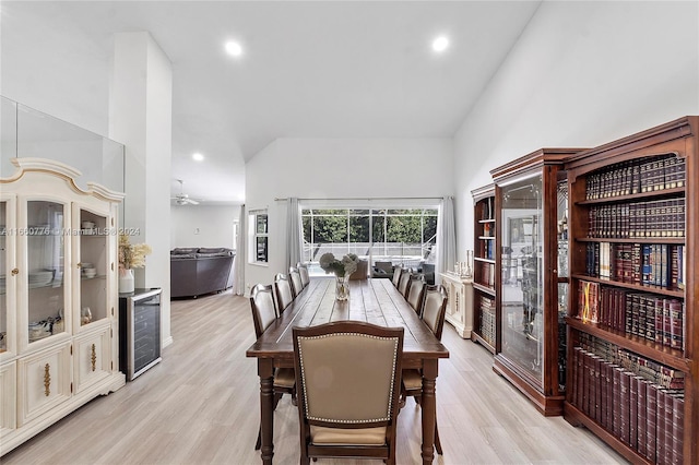 dining space featuring high vaulted ceiling, beverage cooler, and light hardwood / wood-style floors