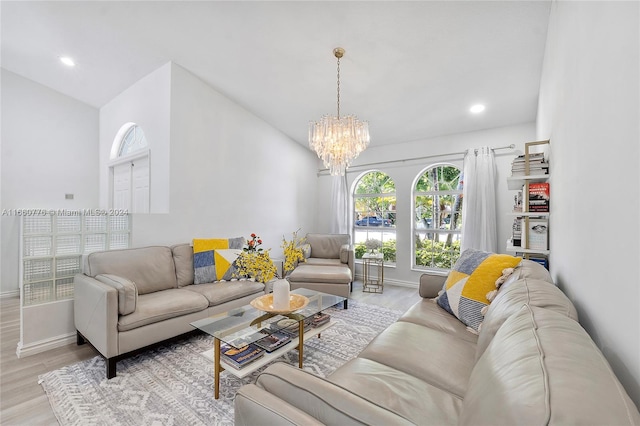 living room featuring an inviting chandelier, light hardwood / wood-style flooring, and vaulted ceiling