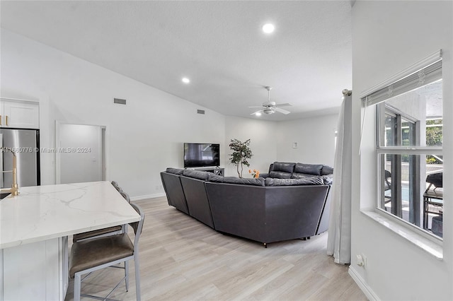 living room featuring a textured ceiling, lofted ceiling, ceiling fan, and light hardwood / wood-style flooring