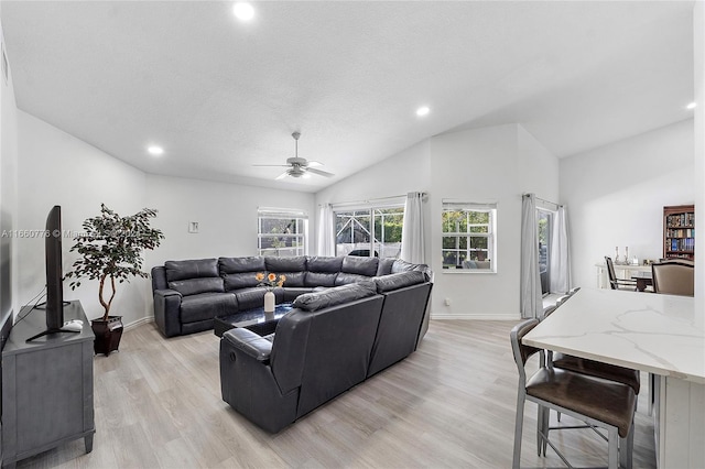 living room with ceiling fan, a textured ceiling, lofted ceiling, and light hardwood / wood-style floors