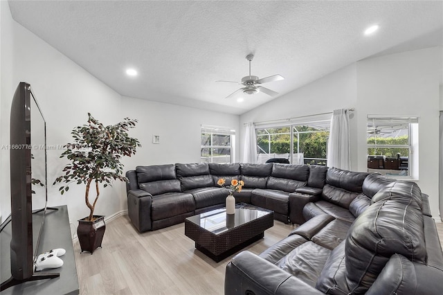 living room with ceiling fan, lofted ceiling, plenty of natural light, and light hardwood / wood-style flooring