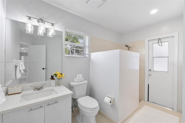 bathroom with a tile shower, vanity, tile patterned flooring, and toilet