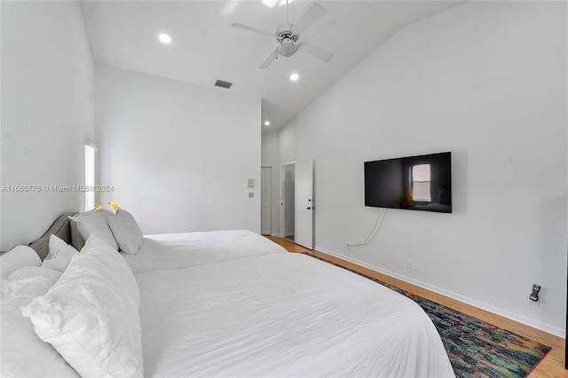 bedroom with ceiling fan, hardwood / wood-style flooring, and high vaulted ceiling