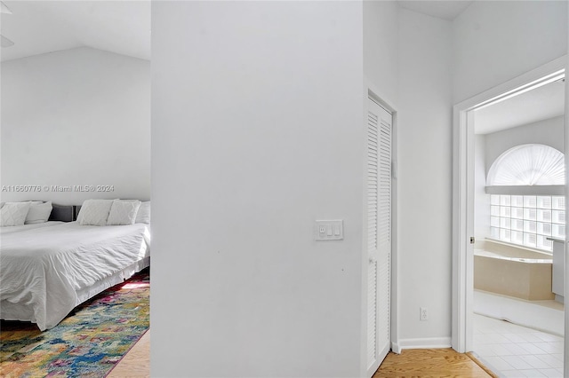 bedroom with lofted ceiling, a closet, and light hardwood / wood-style flooring