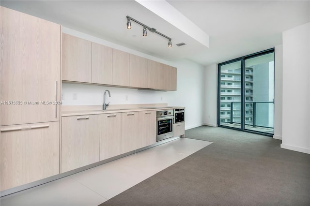 kitchen featuring visible vents, oven, floor to ceiling windows, a sink, and light brown cabinetry