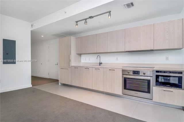 kitchen featuring visible vents, light brown cabinets, and stainless steel oven