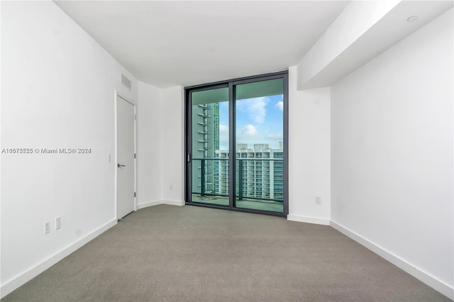unfurnished room with visible vents, carpet floors, baseboards, and a wall of windows