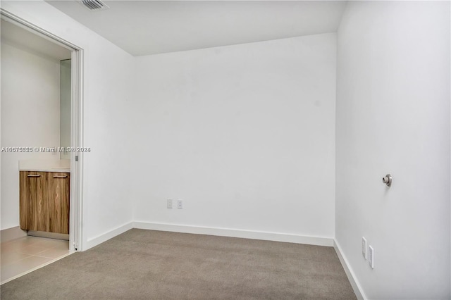 unfurnished room featuring carpet, visible vents, and baseboards