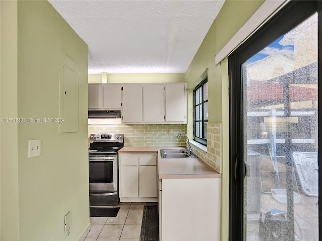 kitchen featuring light tile patterned floors, sink, a textured ceiling, backsplash, and electric stove