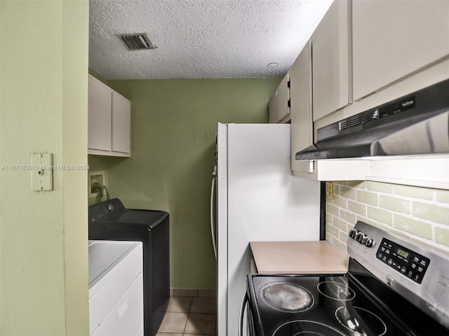 kitchen with light tile patterned floors, a textured ceiling, backsplash, washing machine and dryer, and stainless steel range with electric cooktop