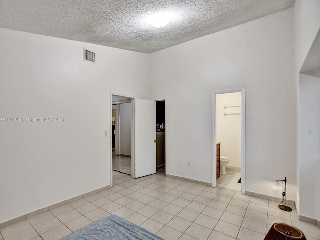 tiled spare room with a textured ceiling and a towering ceiling