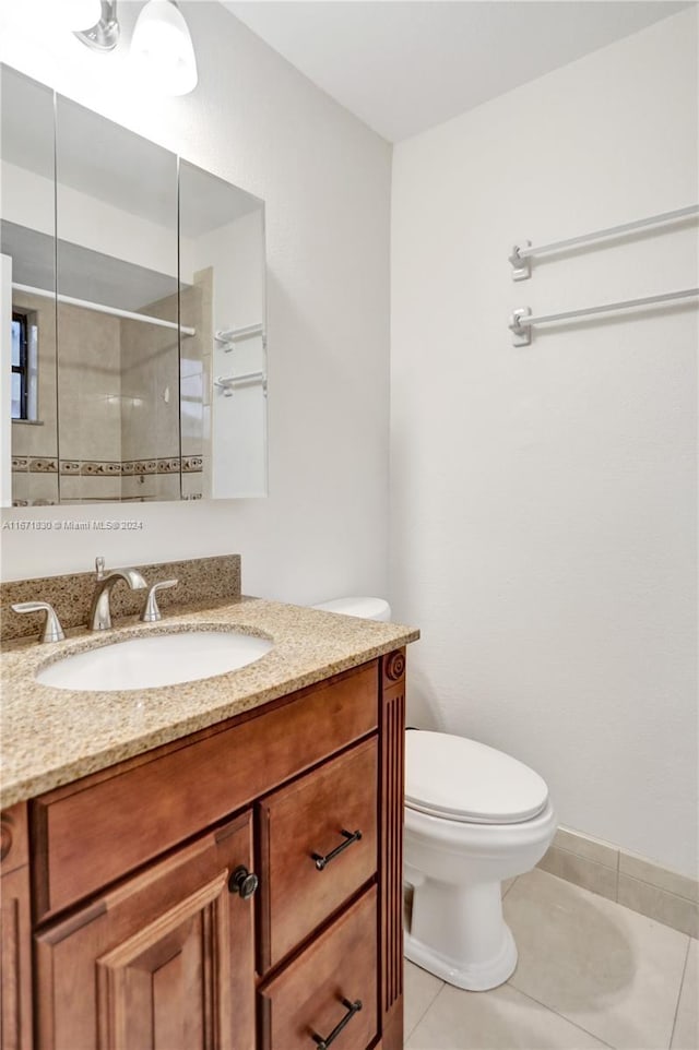 bathroom featuring tiled shower, tile patterned floors, vanity, and toilet