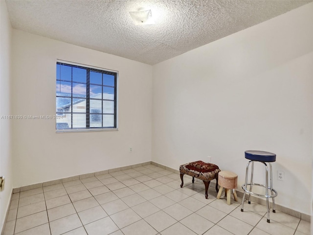 empty room featuring a textured ceiling and light tile patterned floors