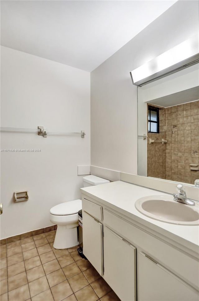 bathroom with tile patterned floors, vanity, tiled shower, and toilet