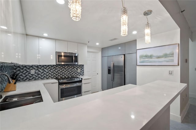 kitchen featuring stainless steel appliances, tasteful backsplash, white cabinets, sink, and decorative light fixtures