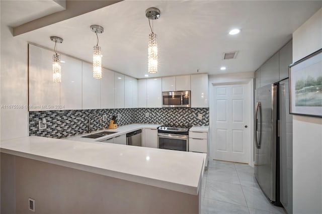 kitchen with appliances with stainless steel finishes, kitchen peninsula, pendant lighting, and sink