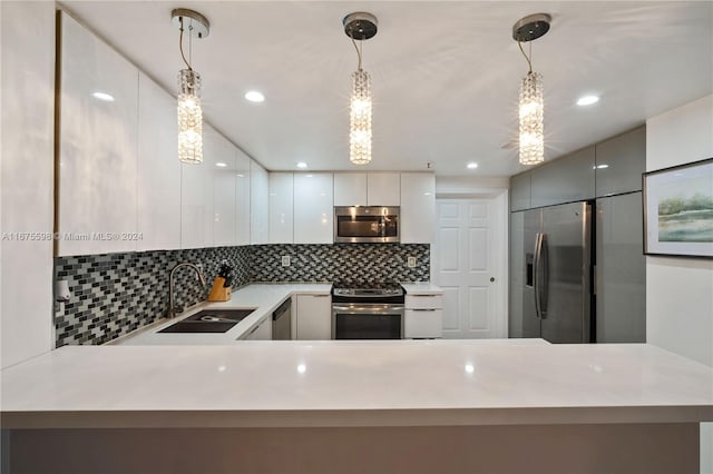 kitchen with pendant lighting, tasteful backsplash, sink, appliances with stainless steel finishes, and white cabinetry