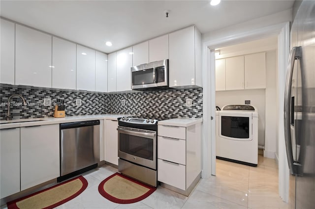 kitchen featuring stainless steel appliances, washer / clothes dryer, white cabinets, and tasteful backsplash