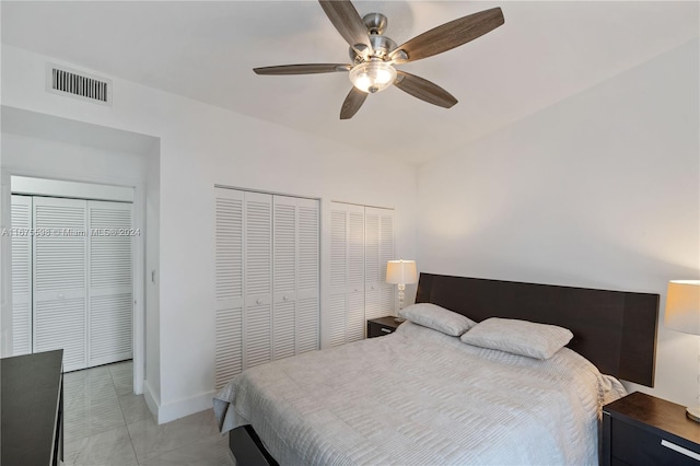 tiled bedroom featuring ceiling fan and two closets