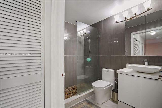 bathroom featuring vanity, tile walls, toilet, and a shower with shower door