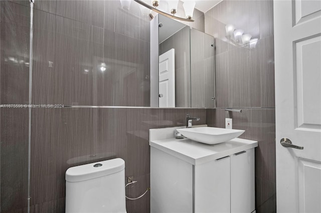 bathroom with toilet, vanity, and tile walls