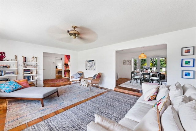 living room with ceiling fan, a textured ceiling, and hardwood / wood-style floors