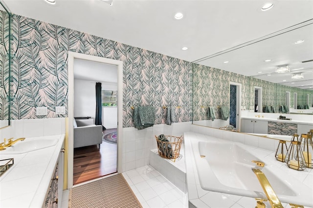 bathroom with tiled tub, vanity, and wood-type flooring