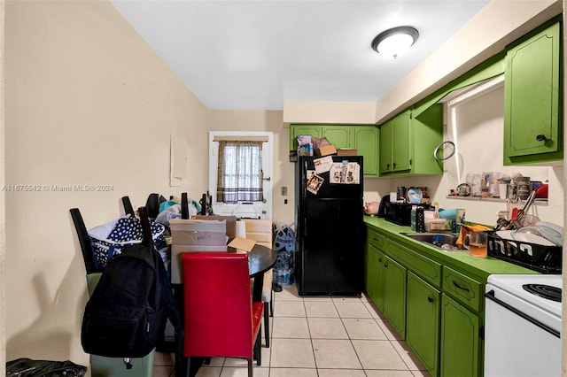 kitchen featuring black fridge, sink, light tile patterned floors, green cabinetry, and electric stove