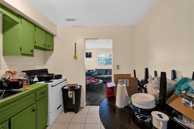 kitchen with green cabinetry, electric stove, and light tile patterned floors