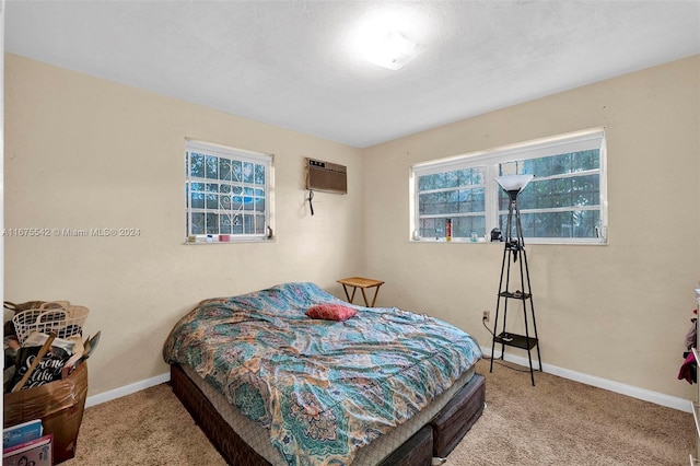 bedroom with multiple windows, a wall unit AC, and carpet floors