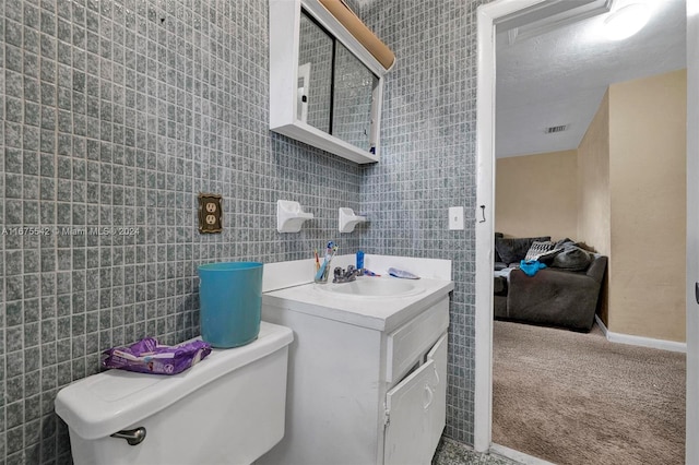 bathroom with vanity, tile walls, toilet, and a textured ceiling