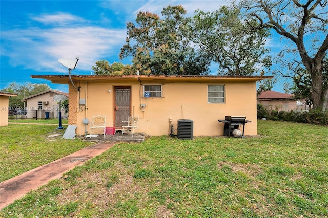 back of house with central AC and a lawn