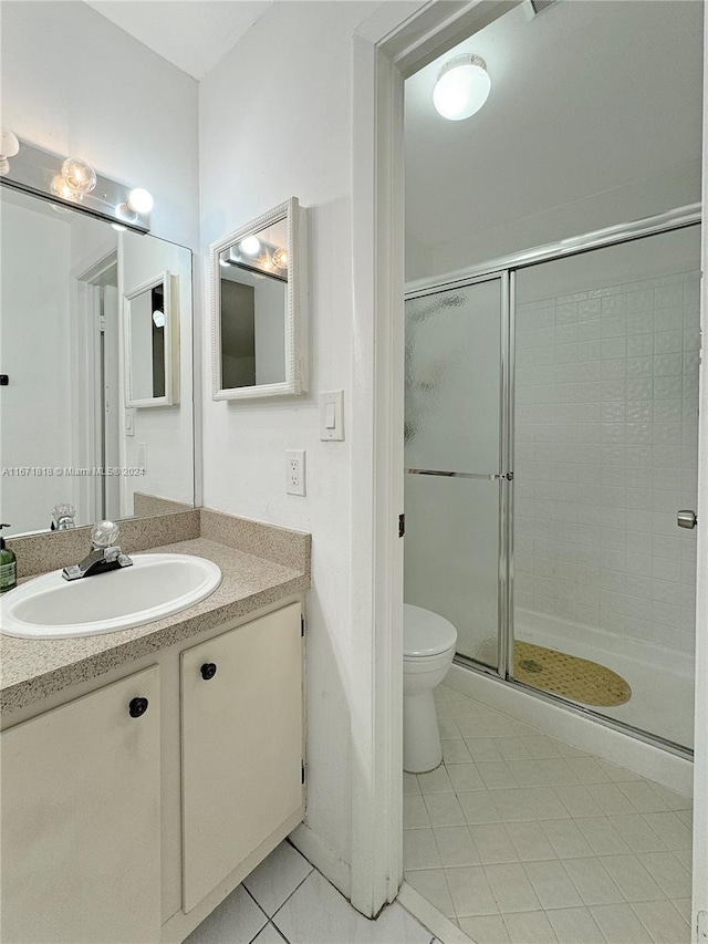 bathroom featuring tile patterned floors, a shower with door, vanity, and toilet