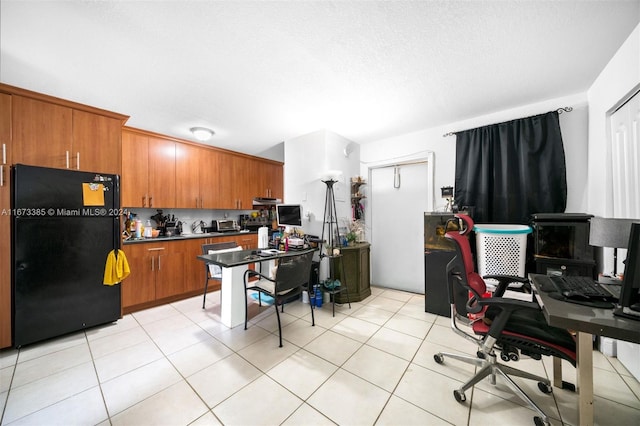 kitchen featuring black refrigerator, light tile patterned floors, and a textured ceiling