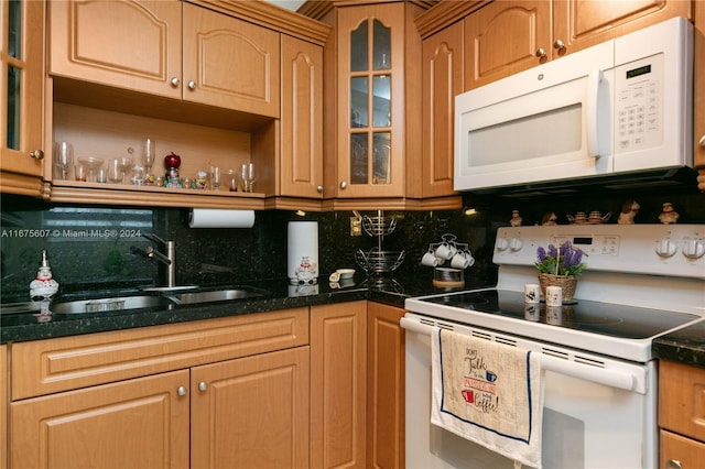 kitchen featuring dark stone counters, white appliances, sink, and tasteful backsplash