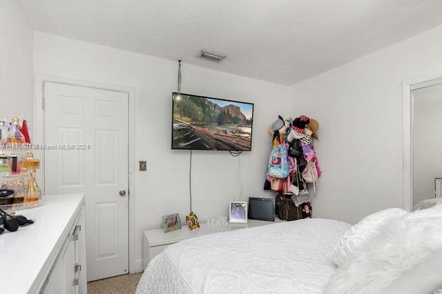 bedroom with light carpet and a textured ceiling