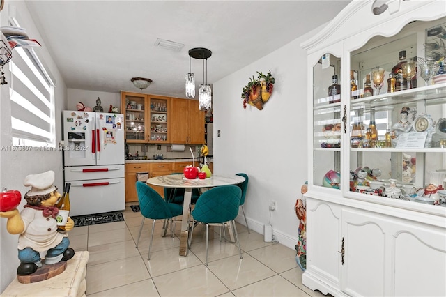 kitchen featuring white refrigerator with ice dispenser, decorative light fixtures, light tile patterned floors, and a healthy amount of sunlight