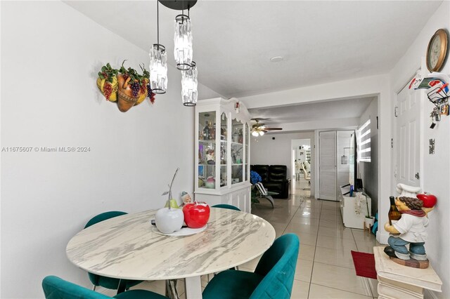 dining area featuring ceiling fan with notable chandelier and light tile patterned flooring