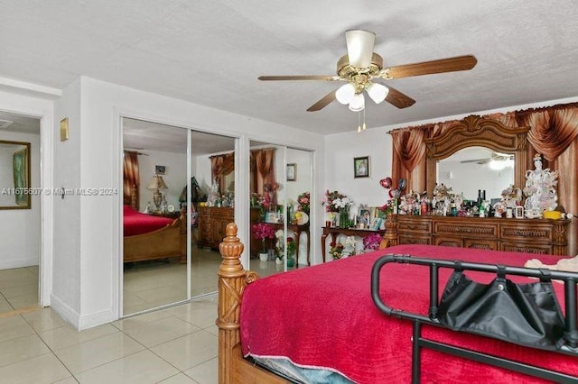 bedroom with tile patterned floors, ceiling fan, two closets, and a textured ceiling