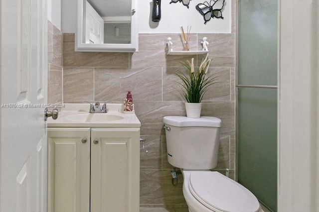 bathroom with vanity, tile walls, and toilet