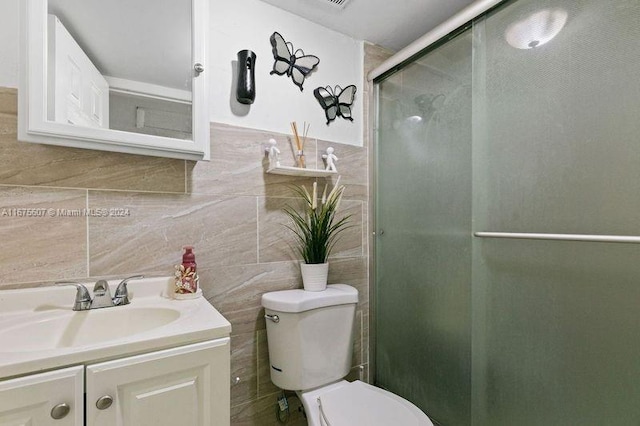 bathroom featuring an enclosed shower, vanity, tile walls, and toilet