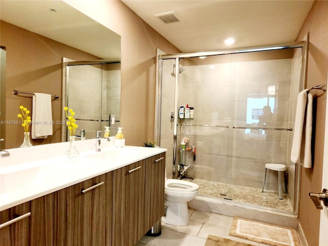 bathroom with tile patterned floors, a shower with door, toilet, and vanity