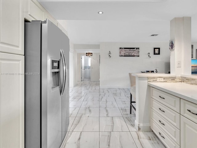 kitchen with an inviting chandelier, stainless steel fridge with ice dispenser, and white cabinets